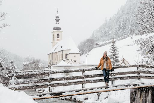 A beautiful view of a Caucasian woman standing on the fence on the frozen covered in snow background