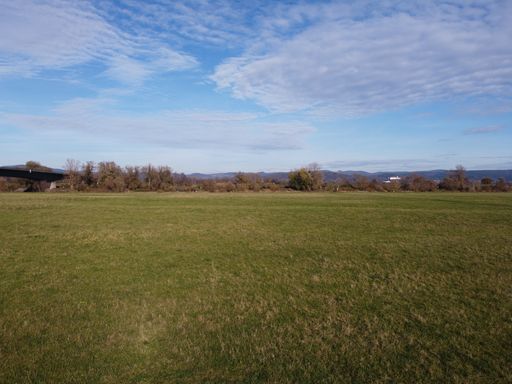 A view of a grassy field under a cloudy blue sky