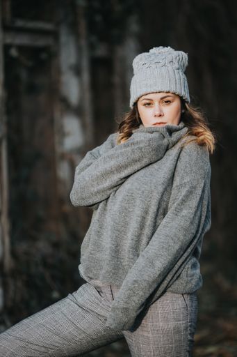 A vertical selective focus shot of a young lady wearing a gray turtleneck sweater