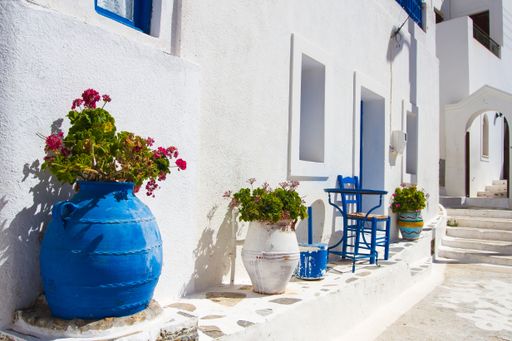 A beautiful shot of a white street with plants and chairs in Amorgos, Greece