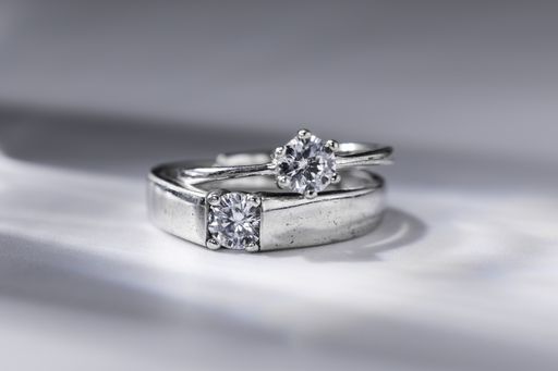 A closeup shot of a couple of diamond rings on a white surface