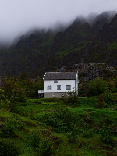 A lone white house on the slope of a mountain in Lofoten, Norway