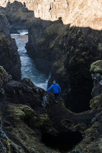 A vertical shot of a person standing on the edge of a cliff