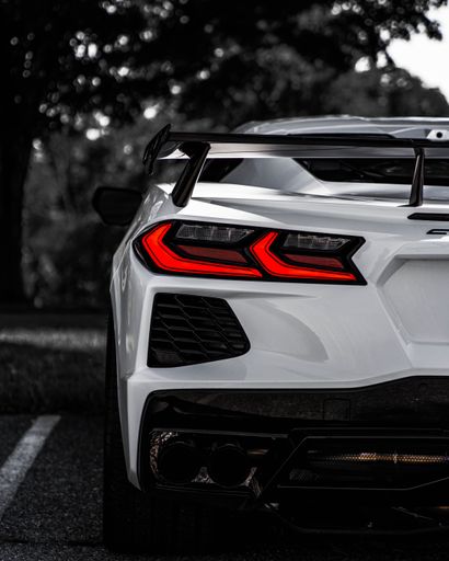 A selective color vertical of the back of a white Chevrolet Corvette C8 sportscar in a parking lot