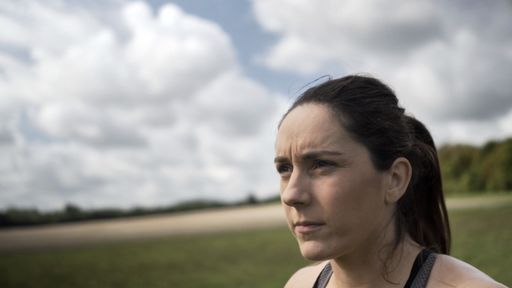 A closeup of an athletic Caucasian woman working out at a field on a cloudy day