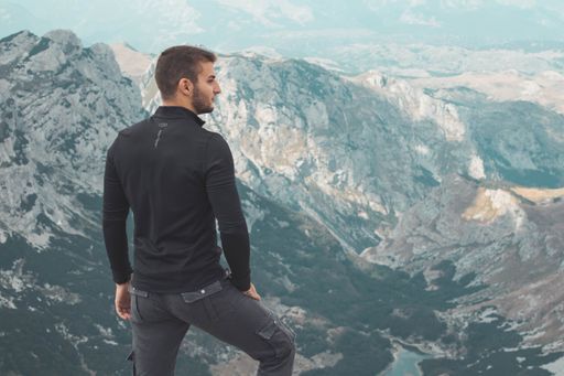 A man in black and gray standing on the top of the Durmitor mountain looking aside