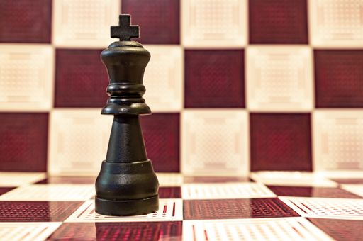 A selective focus closeup of a black king chess piece on a chessboard