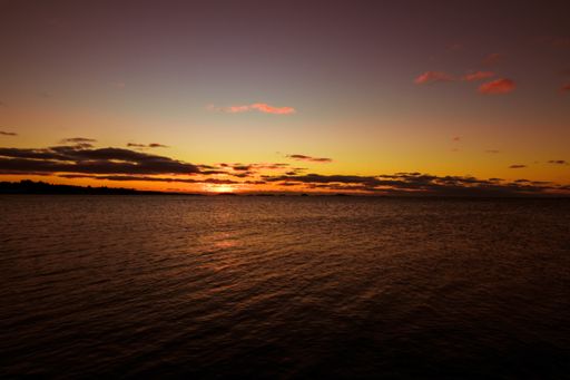 A beautiful setting down sunset sun on the horizon and a calm waveless lake water