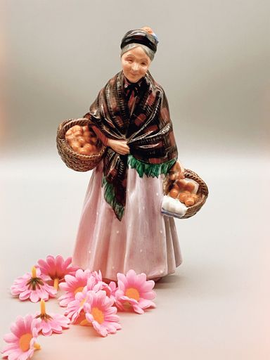 A vertical shot of a vintage old woman porcelain figurine