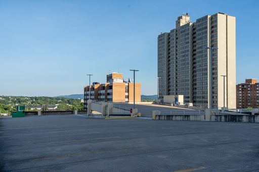 A skyscraper at the end of the top floor of a parking garage