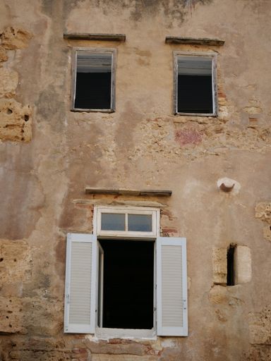 A low angle view of an abandoned building with broken windows and weathered walls