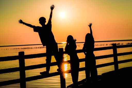 A beautiful shot of silhouettes of happy teenagers on a pier at sunset