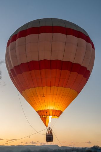 A vibrant hot air balloon soaring in a picturesque sunset sky