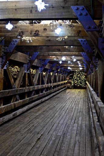 A plank wooden gazebo covered in Christmas lights and decorations during the night