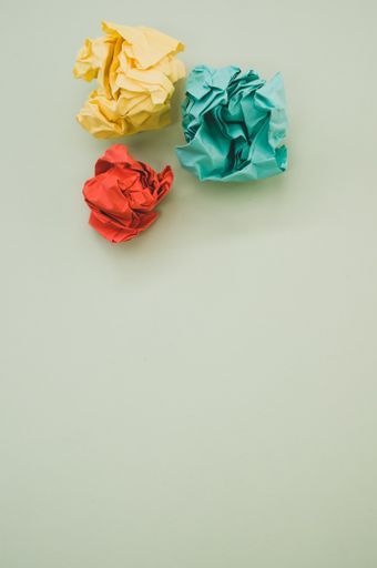 A vertical top view of green, yellow, and red crumpled papers on pastel green background