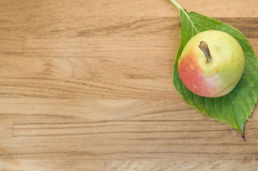 A top view of a pear on a leaf on a wooden surface