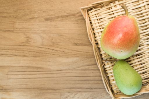 A top view of a wooden plate with two pears on a wooden surface