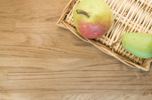A top view of a wooden plate with two pears on a wooden surface