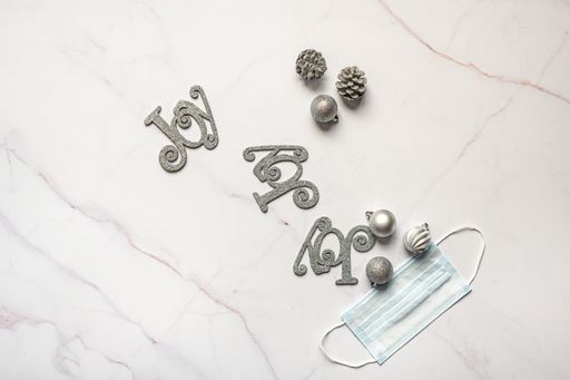 A top view of face mask and Christmas ornaments on marble surface-new normal