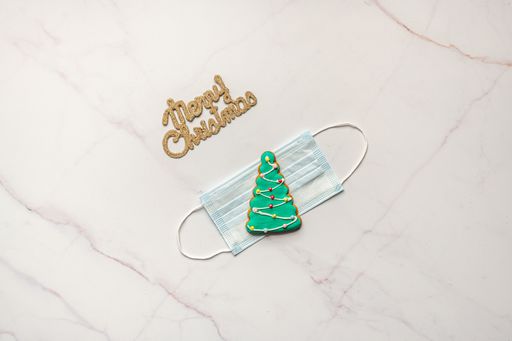 A top view of face mask with Christmas ornaments on marble surface