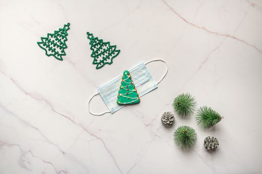 A top view of face mask and Christmas ornaments on marble surface
