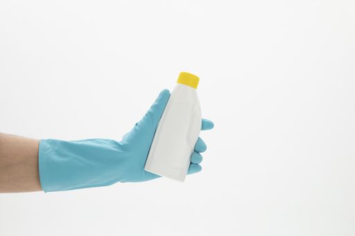 A selective focus closeup of a hand wearing a glove while holding a detergent bottle-concept COVID19 prevention