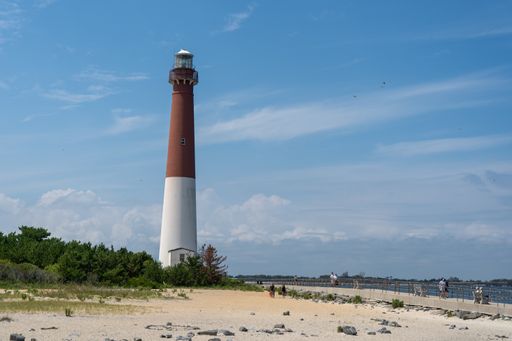 The Barnegat Lighthouse on the shore of the sea against the cloudy sky