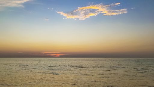 A landscape of a sea under a blue cloudy sky during a beautiful sunset