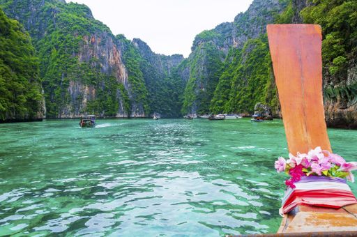 A landscape of Phi Phi Islands covered in greenery surrounded by boats under sunlight