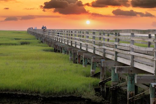 Colorful Cape Cod sunset over long raised wooden boardwalk spanning protected saltwater marsh at Grays Beach, Yarmouth Port, Massachusetts.