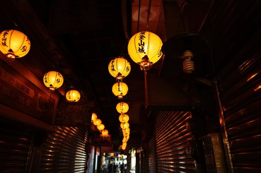 A closeup of Chinese paper lantern with lights surrounded by buildings with a blurry background