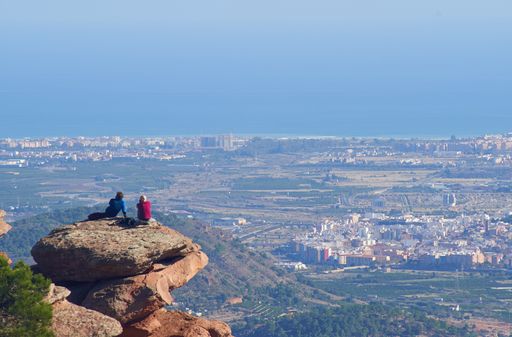 A beautiful view of people sitting on a cliff and enjoying the beautiful view of the landscape