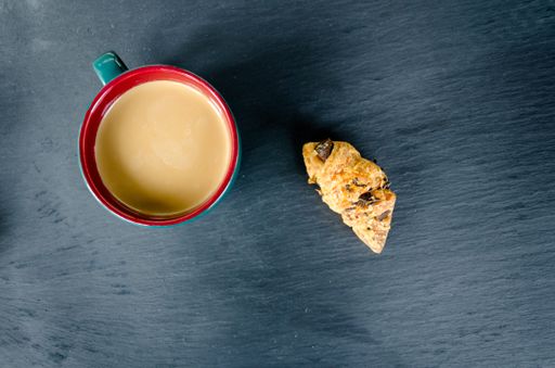 A top view of green cup of tea with milk and croissant on table