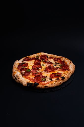 A vertical shot of a delicious pizza on a black surface
