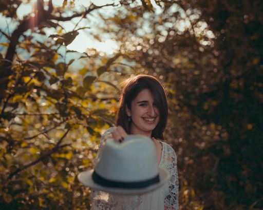 A shallow focus shot of a Hispanic female holding a hat in a field