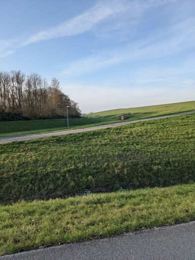 A beautiful shot of an asphalt road through the green field under the blue sky