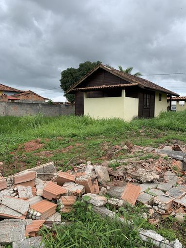 A vertical shot of bricks on the ground with a small house in the countryside on the background
