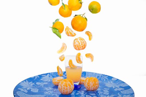A closeup shot of tangerines over tangerine juice in a glass on a plate