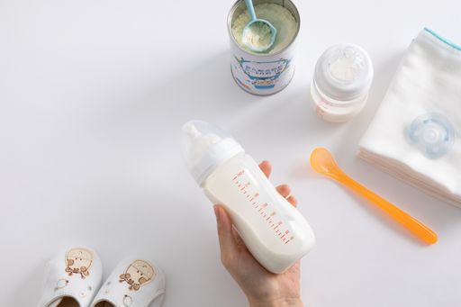 A high angle shot of a female hand and baby care items on white surface