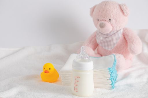 A closeup shot of a bottle of milk for a newborn baby with baby care items in the background