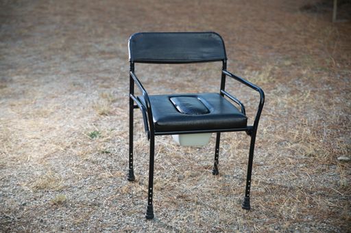 A mobile black leather potty chair outdoors