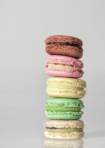 A closeup of colorful macaroons on each other on a table against a white background