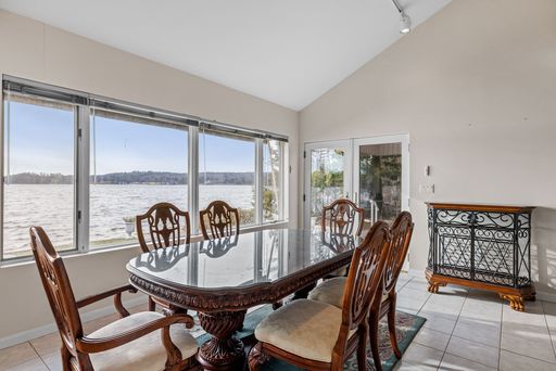 The set of brown table and chairs in the living room with the lake view visible from the window