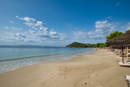 A sandy coastline with deckchairs and a calm seascape view in Koukounaries beach, Skiathos island, Greece