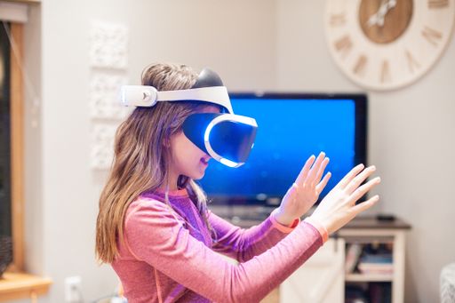 A closeup shot of a little girl trying to touch the object she sees with the virtual reality glasses