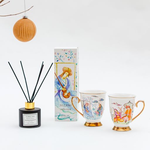 A vertical shot of cups and aroma diffuser set and a Christmas ball on a white background