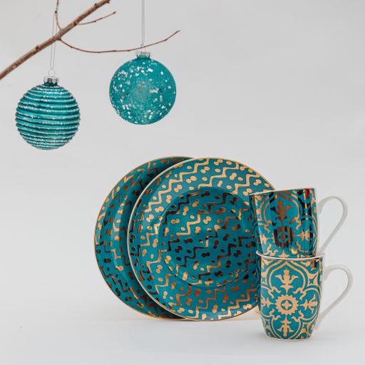 A vertical shot of a plate and cup set and Christmas decorations on a white background