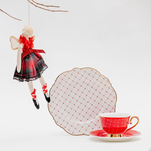 A vertical shot of a plate and cup set and a Christmas toy on a white background