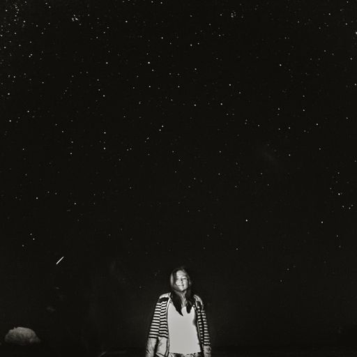 Vertical shot of a girl looking at the starry sky at night on the beach