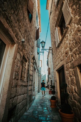 A vertical shot of a man walking along a narrow alley between the buildings